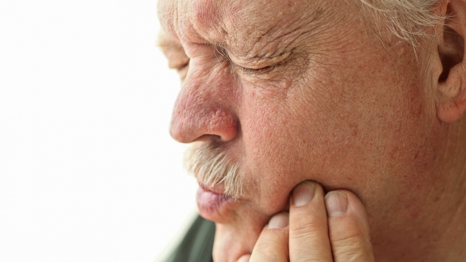 man holding side of his mouth with tooth pain